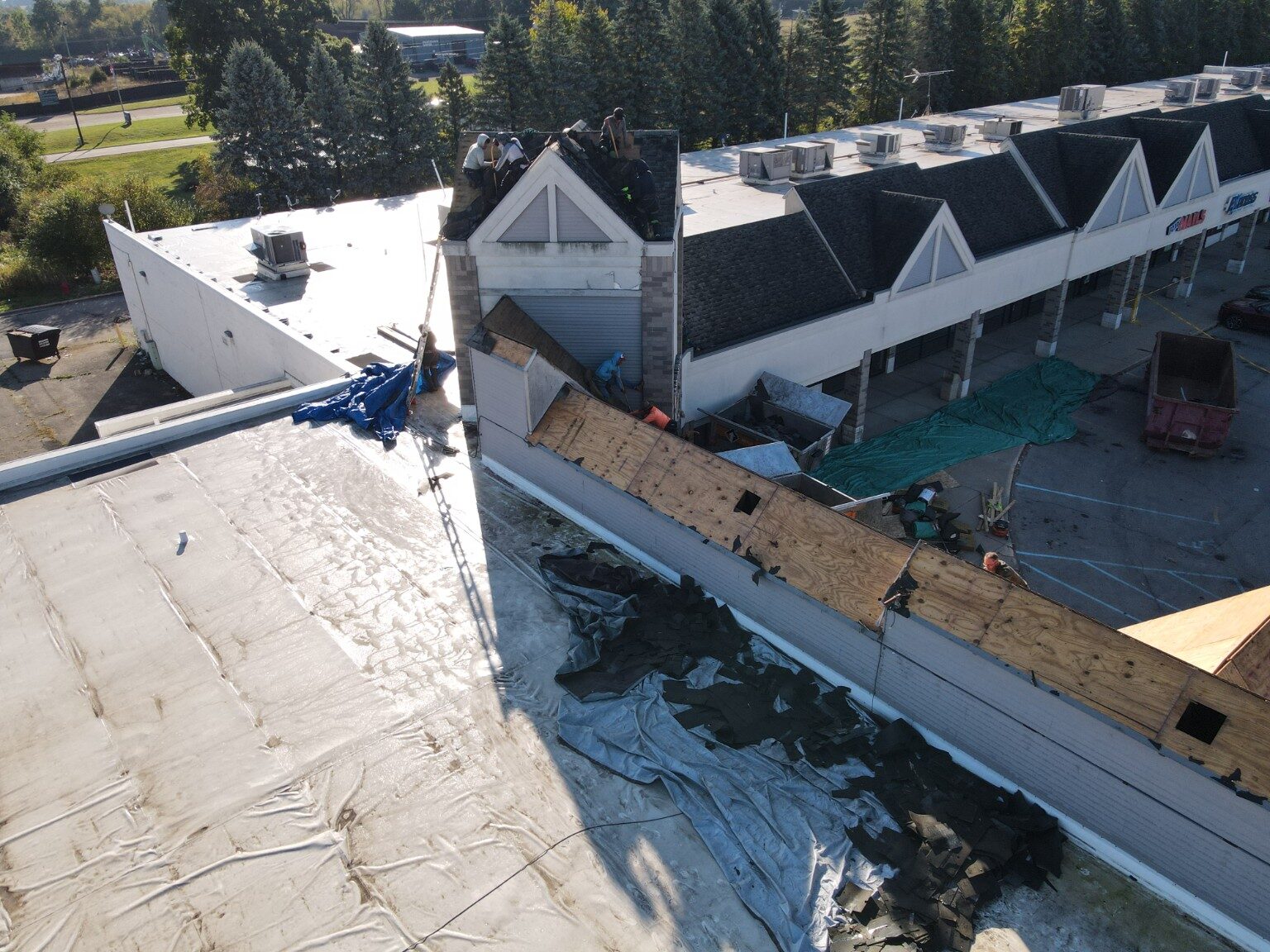 Commercial roof replacement underway around multiple peaked sections