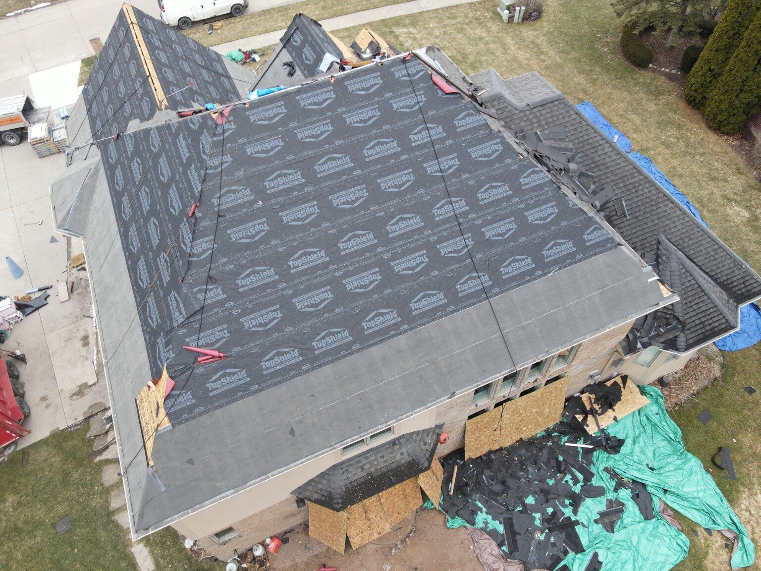 Aerial view of a roofing crew installing underlayment on a large residential roof