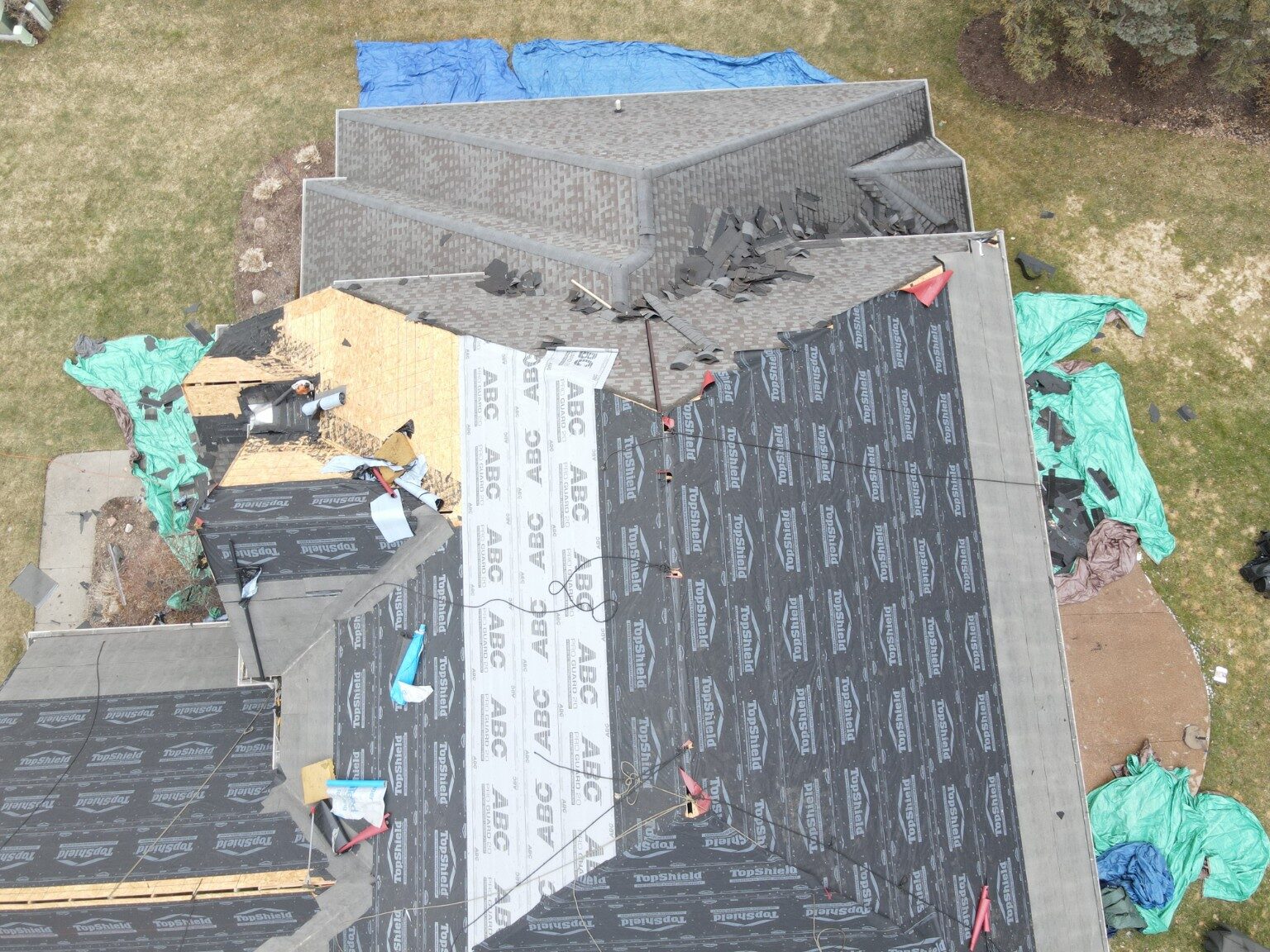 Roofing crew installing underlayment across multiple roof slopes