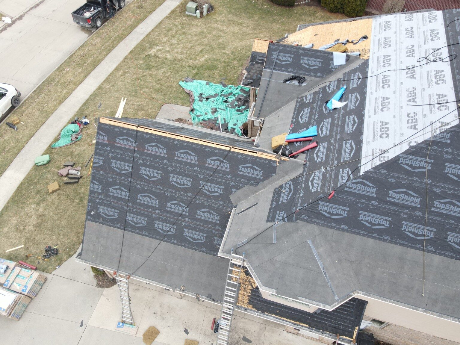 Crew preparing several connected roof sections for new shingles