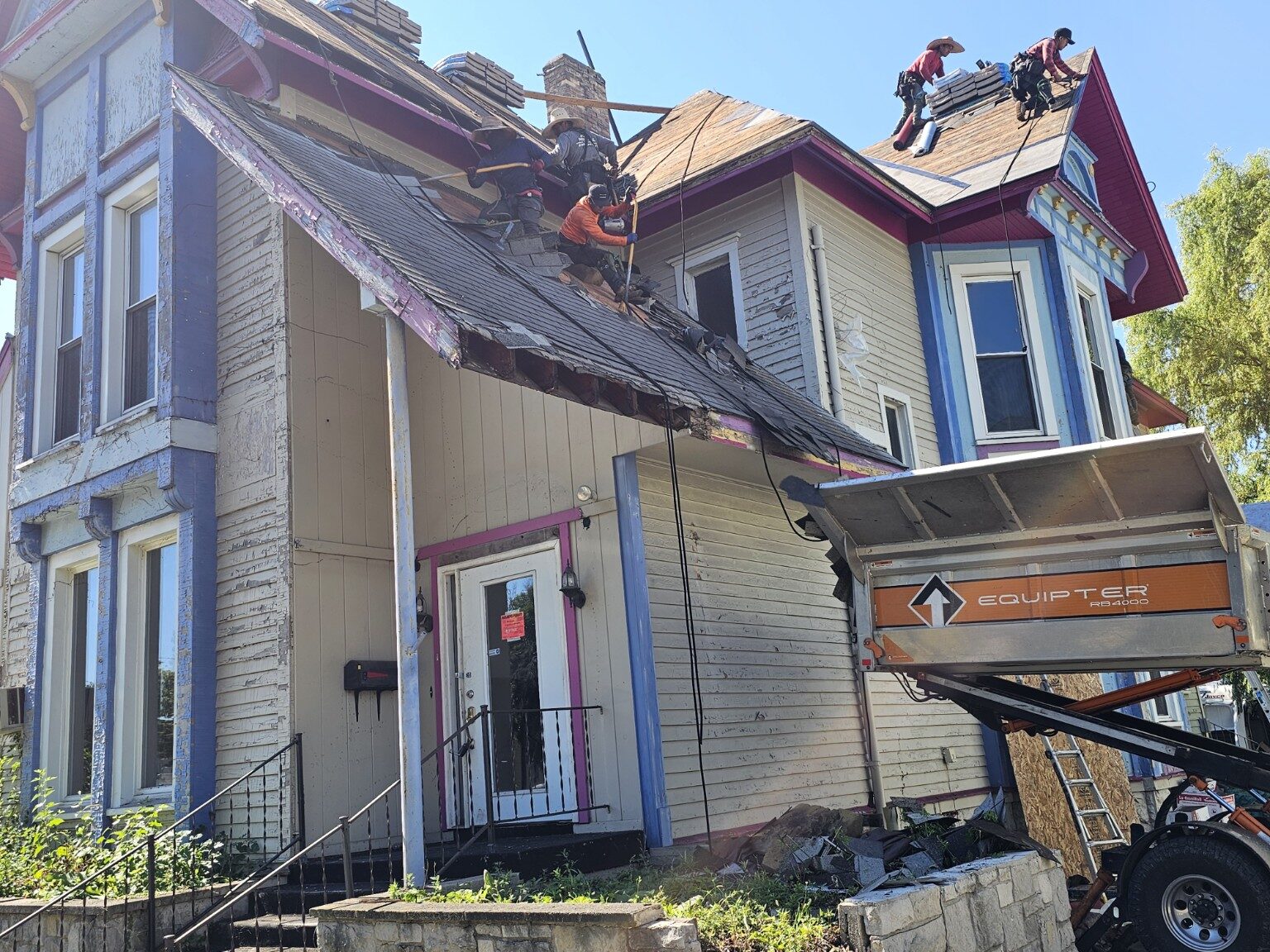 Roofing crew removing old material from a steep historic home