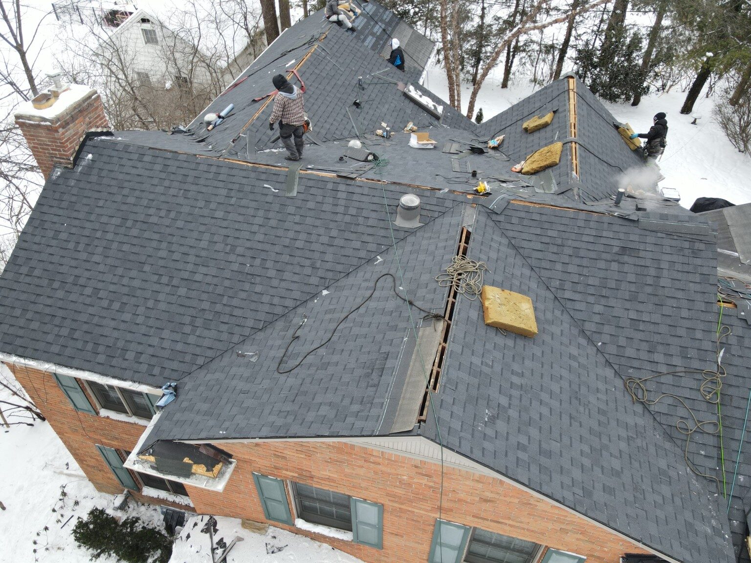 Roofing crew working across a large shingle roof